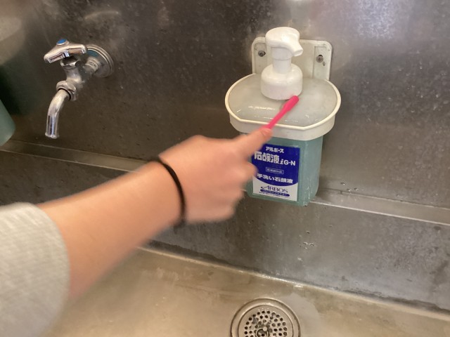 保健委員会が歯ブラシで手洗い場を清掃する写真（手元）