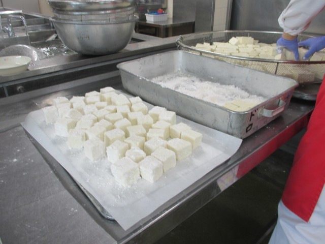 豆腐に１つ１つ丁寧に粉をつけて油で揚げます